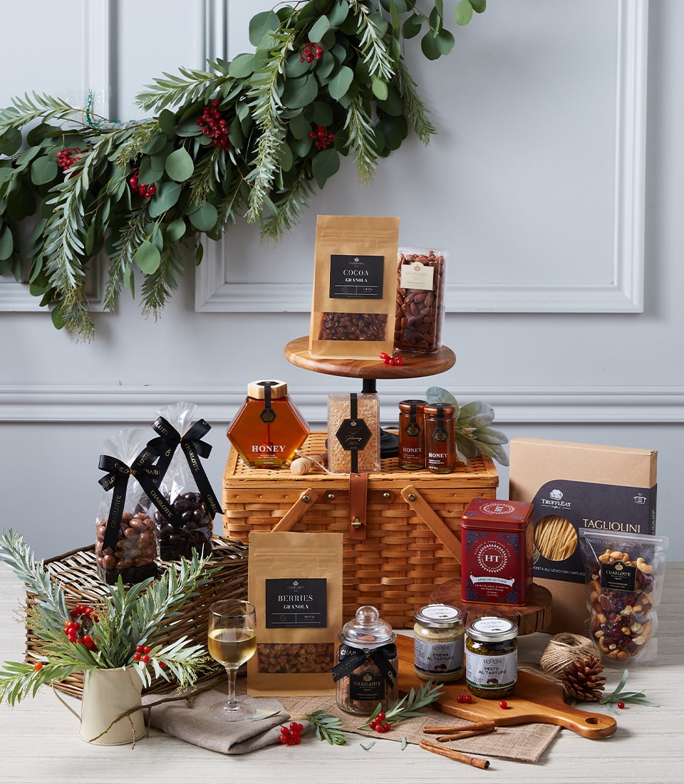 Luxury gourmet gift basket with artisan granola, honey, spreads, pasta, and chocolate-covered nuts in wicker picnic hamper