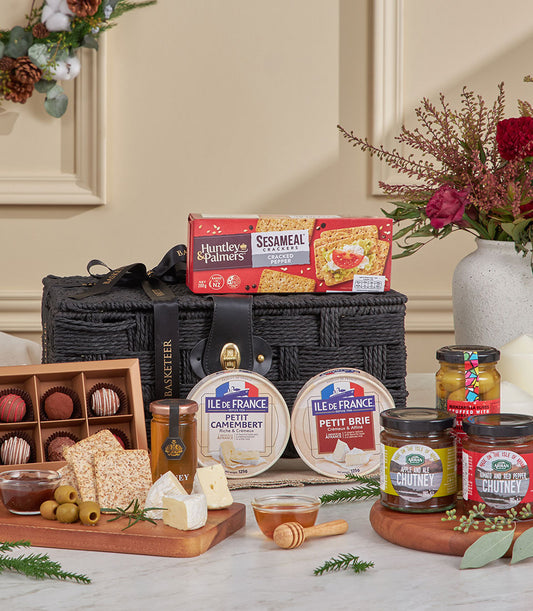 Luxury black woven hamper filled with artisan cheeses, crackers, chutneys, olives, honey, and chocolate truffles