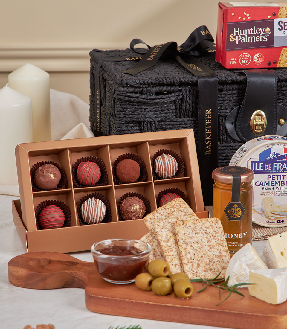 Luxury black woven gift basket with gourmet cheese, crackers, olives, chocolate truffles, and artisan spreads