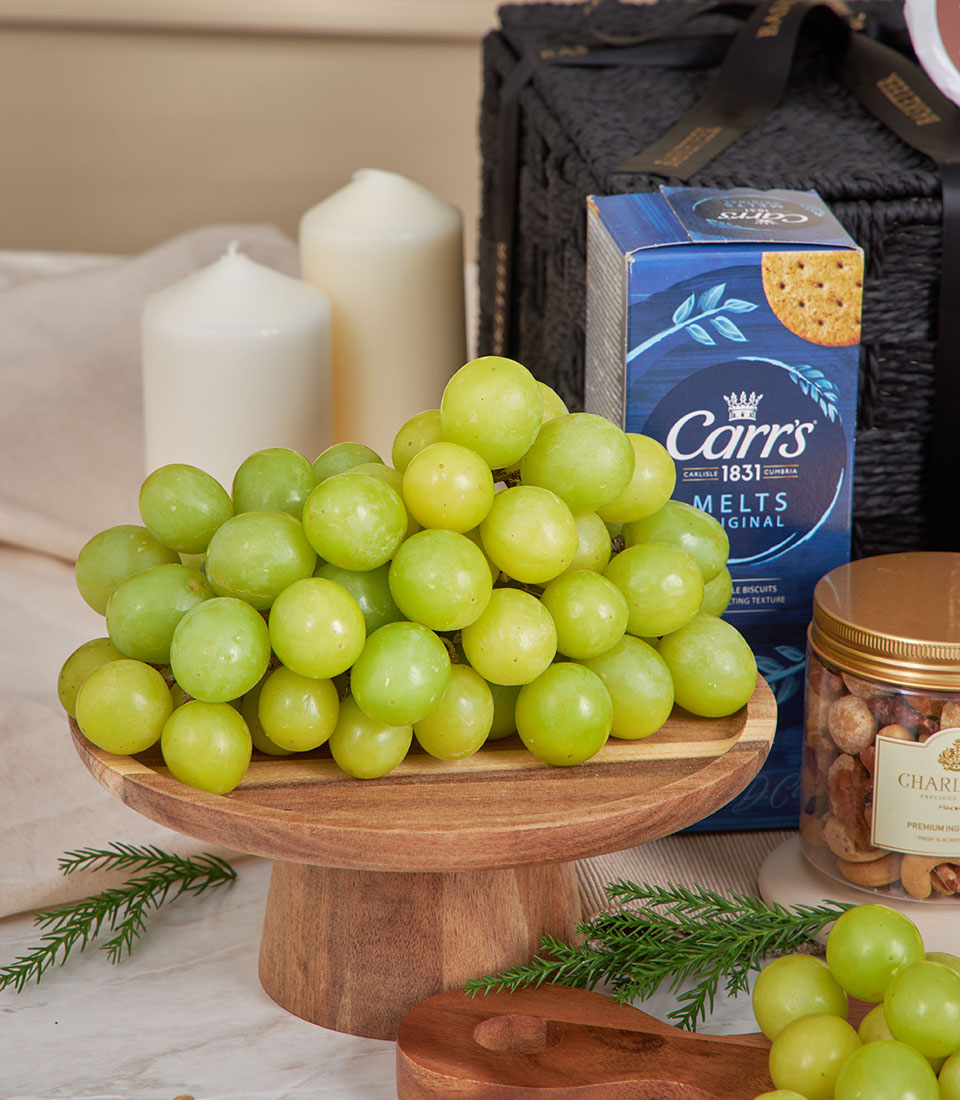 Luxury cheese and gourmet gift basket with fresh grapes, crackers, mixed nuts, and festive candles