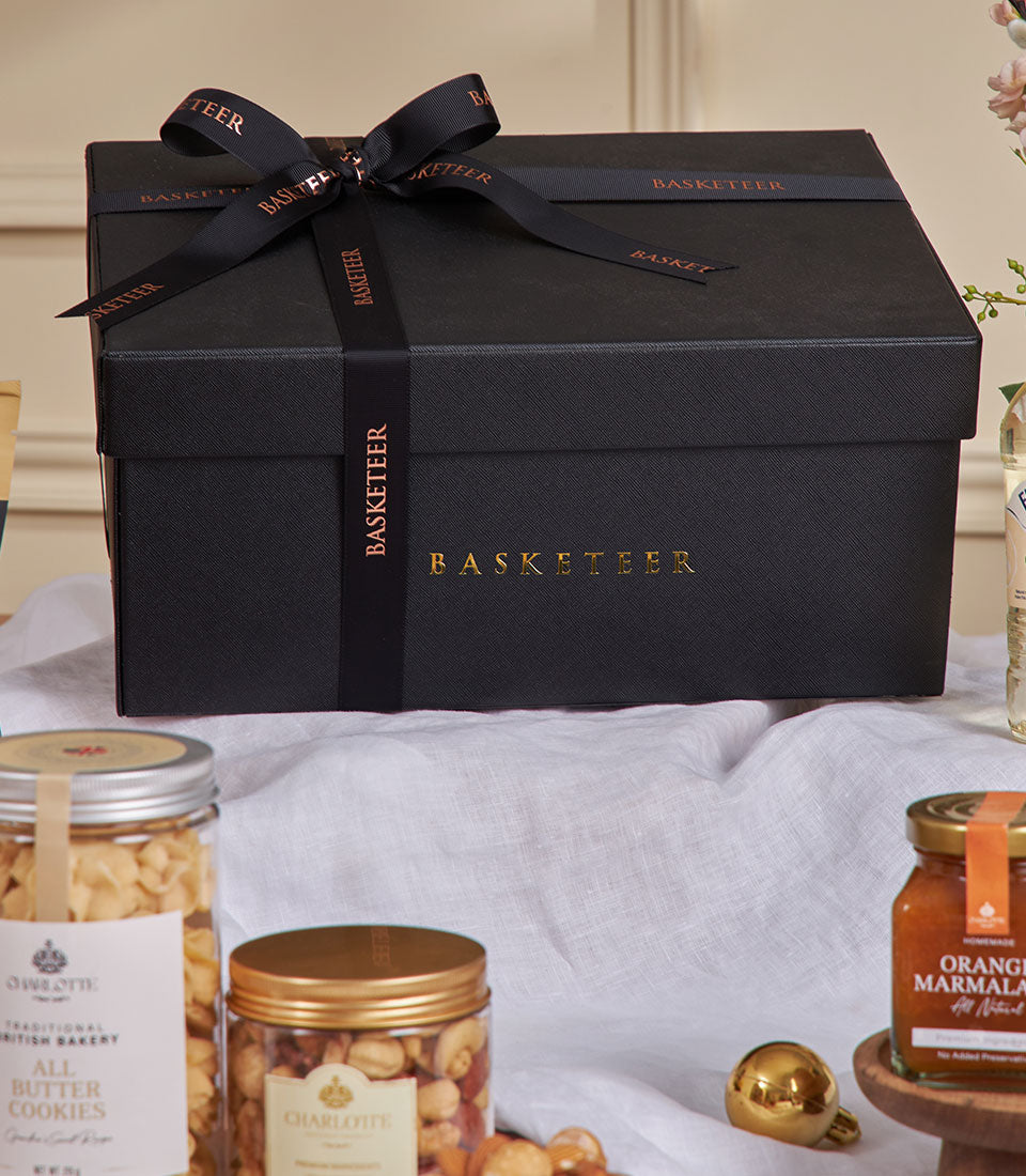 Luxury black gift box with gold Basketeer branding, Earl Grey treats including all-butter cookies, mixed nuts, and orange