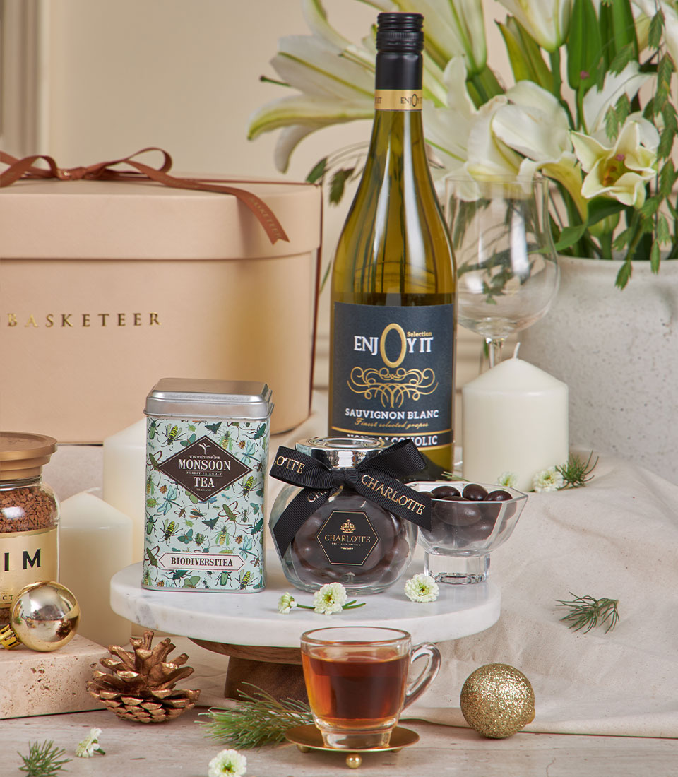 Beige luxury gift basket with tea, wine, Charlotte chocolates, and white lilies for New Year celebrations