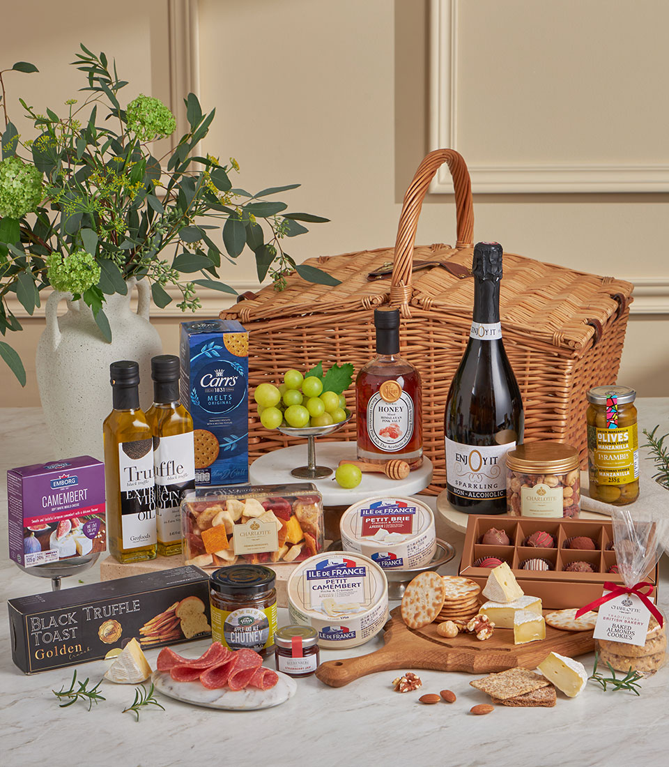 Luxury wicker picnic basket filled with gourmet cheeses, crackers, olives, honey, and artisan treats