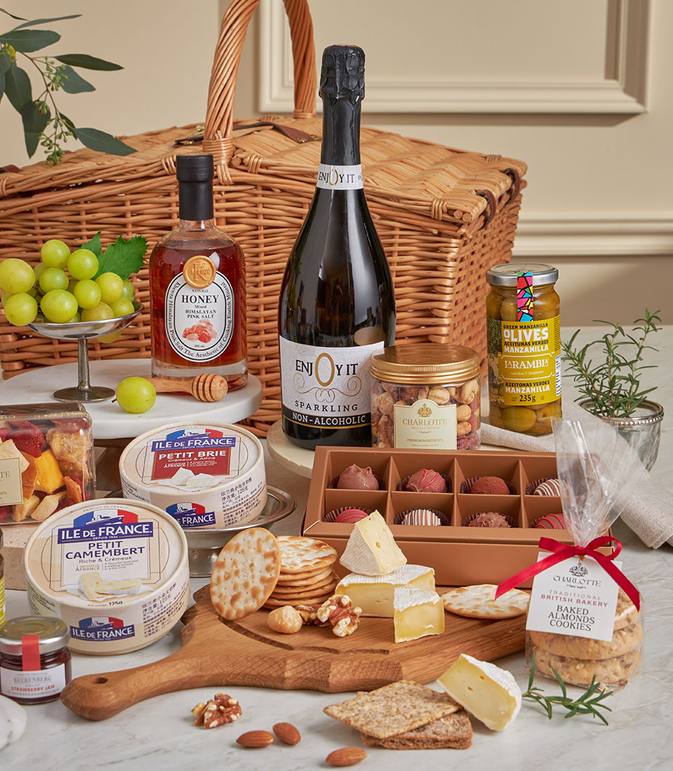 Luxury wicker picnic basket with gourmet cheeses, crackers, chocolates, sparkling beverage, and artisan almond cookies