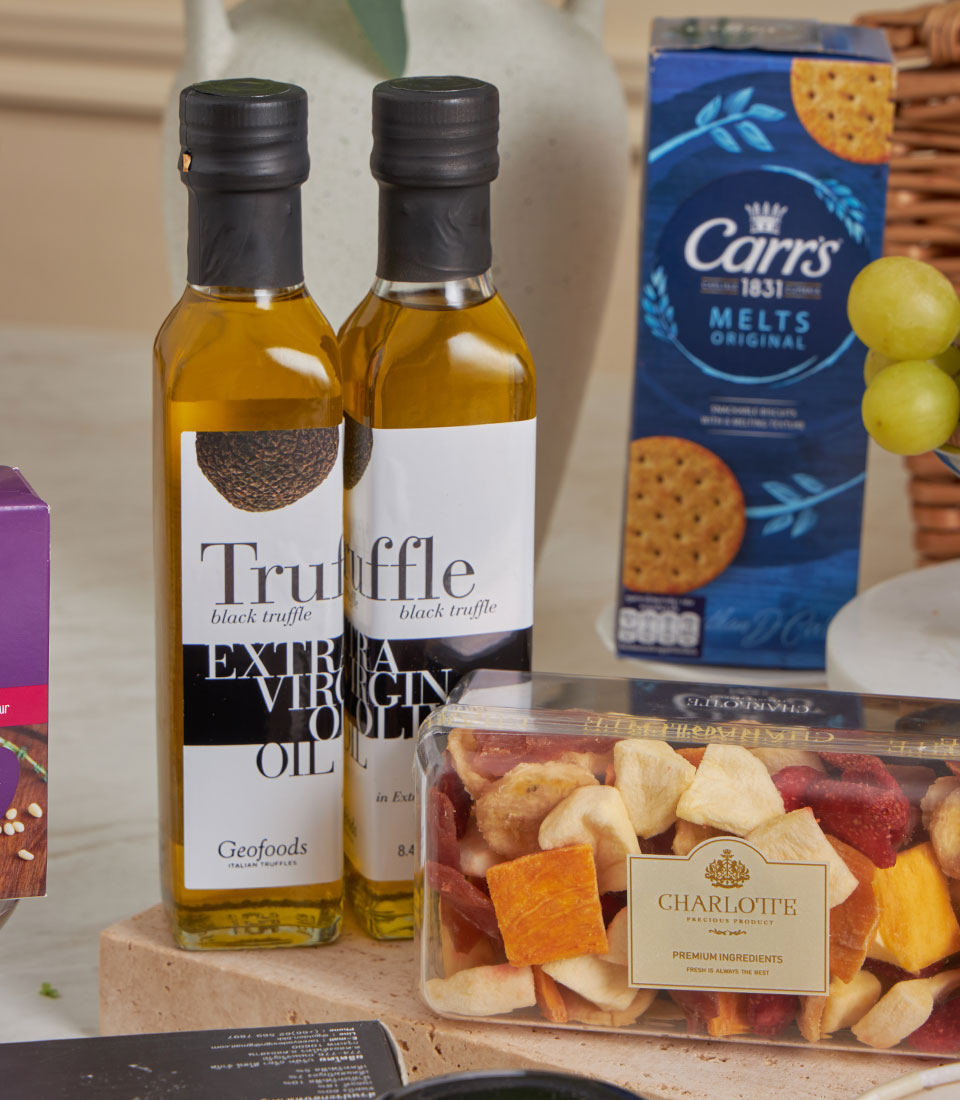 Ultimate gourmet celebration hamper with truffle oil, artisan crackers, dried fruits, and fresh grapes