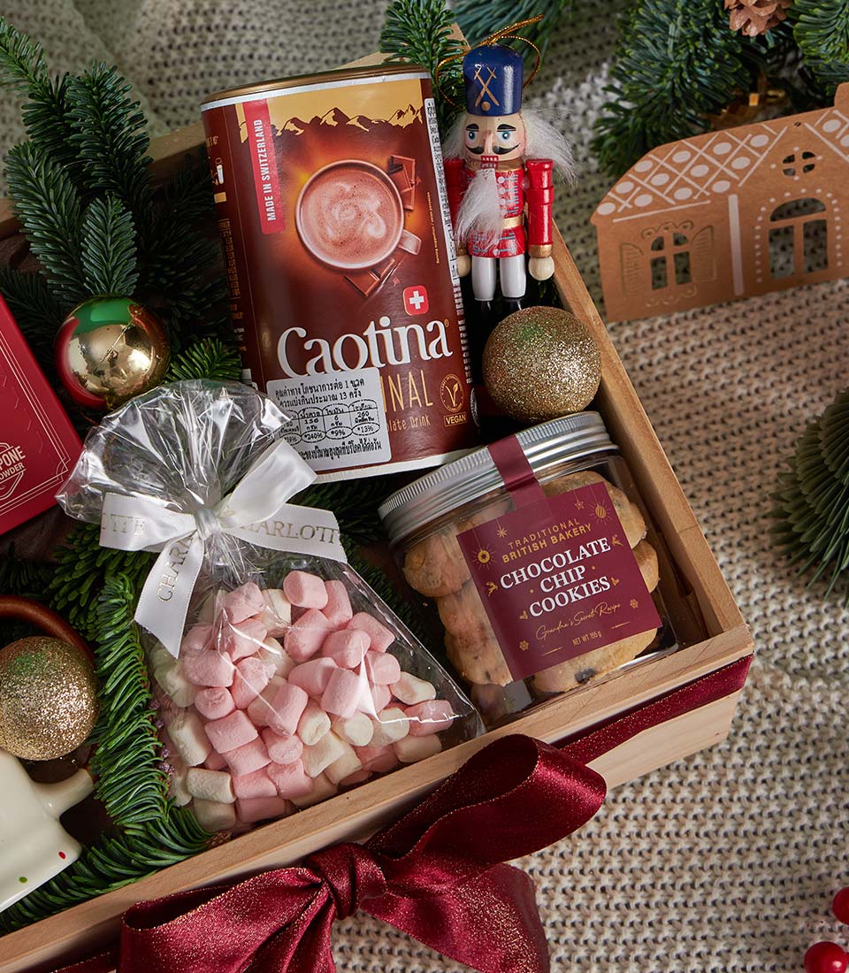 Festive Christmas gift box with Caotina hot chocolate, British bakery cookies, marshmallows, and gold baubles in wooden