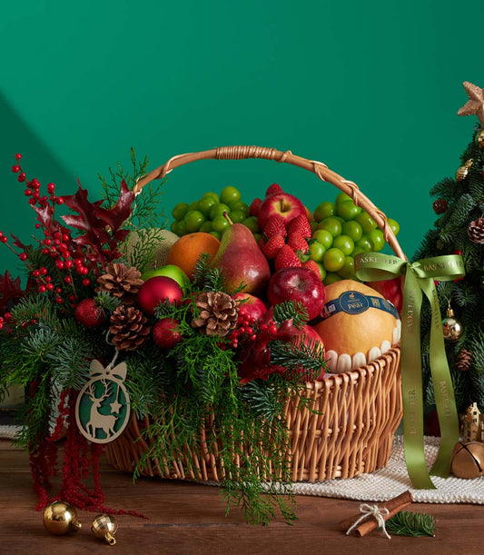 Luxury Christmas fruit basket with fresh grapes, apples, strawberries, oranges and festive pine cone accents