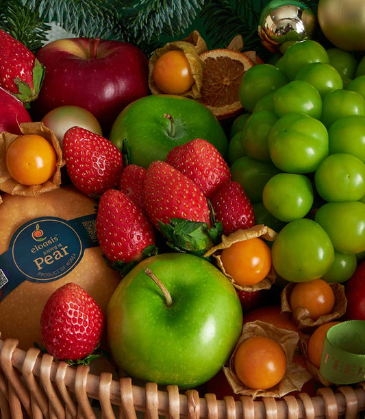 Classic red Christmas fruit basket with apples, pears, strawberries, and festive holiday greenery