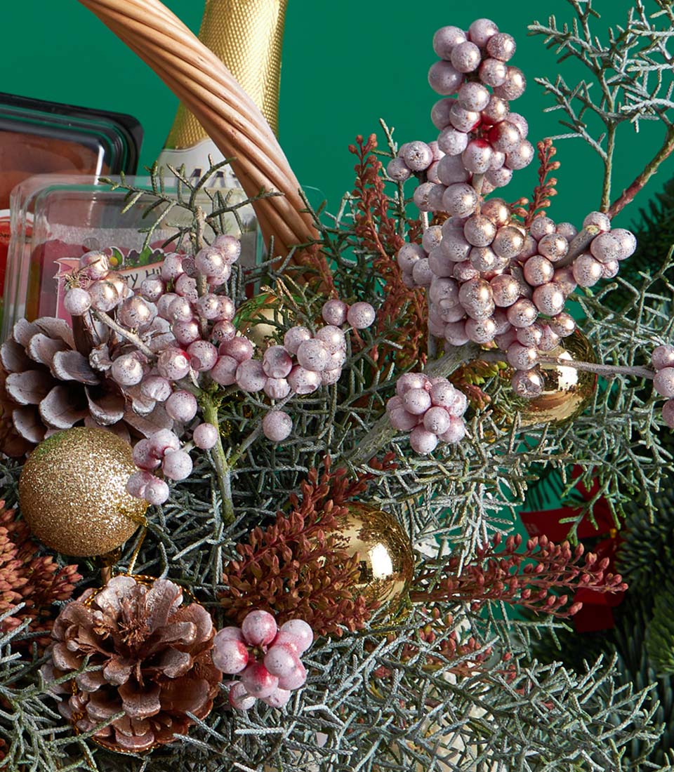 Premium Christmas fruit basket with champagne, gourmet treats, and festive frosted berries in woven gift hamper