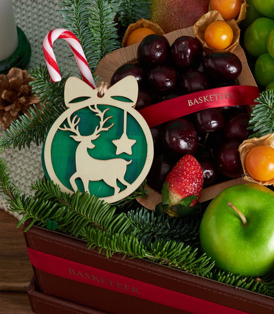 Festive Christmas fruit basket with fresh cherries, apple, strawberries, and candy cane on dark brown leather