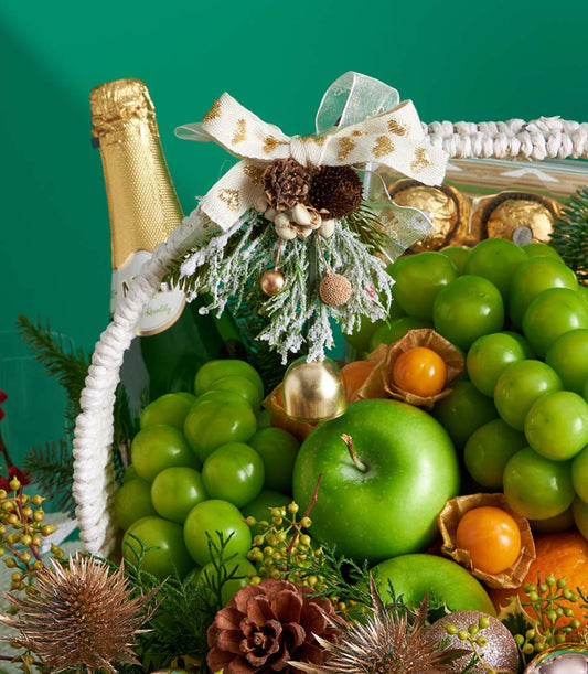 Premium festive fruit and chocolate gift basket with champagne, green grapes, apples, and gold-accented holiday decorations