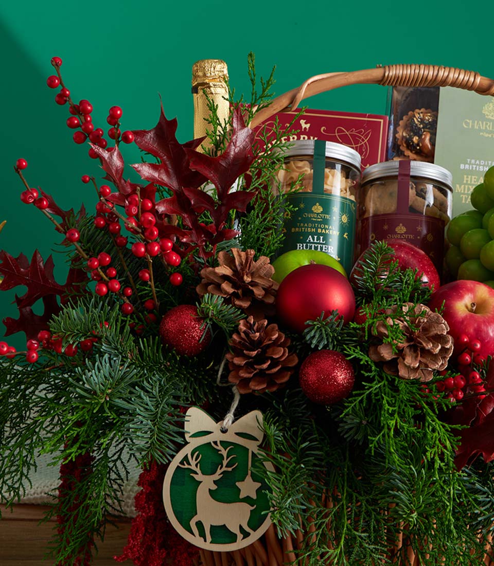 Festive Christmas fruit and cookie gift basket with champagne, fresh apples, grapes, and artisan baked goods nestled in