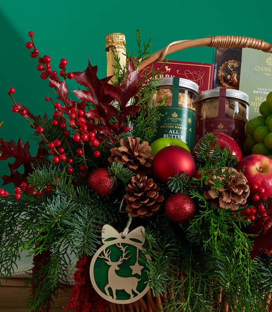 Festive Christmas fruit and cookie gift basket with champagne, fresh apples, grapes, and artisan baked goods nestled in