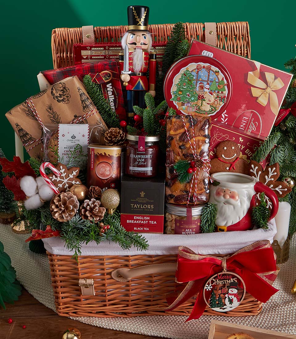 Festive wicker Christmas hamper with gourmet treats, tea, hot chocolate, fruitcake, cookies, and nutcracker decoration