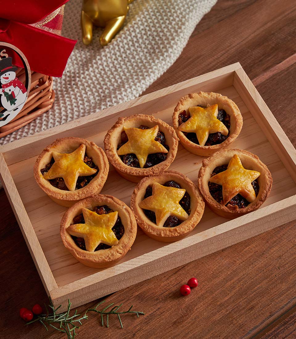 Golden star-topped mince pies in wooden tray, luxury Christmas gift basket with festive berries and greenery