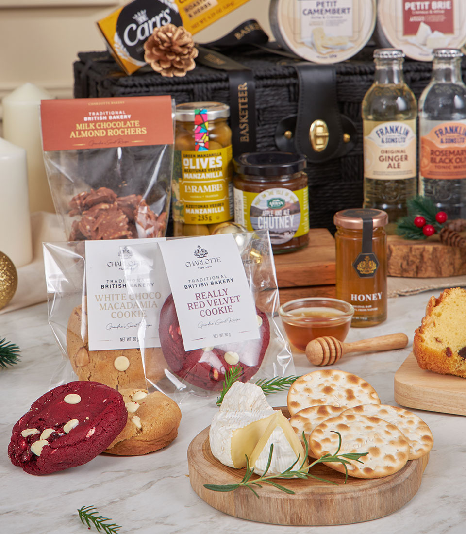 Luxury black woven gift hamper with gourmet cheese, chocolates, olives, honey, and artisan crackers on marble