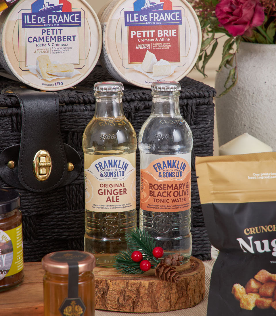 Premium cheese and gourmet snack hamper with Camembert, Brie, artisan beverages, and honey in black woven basket