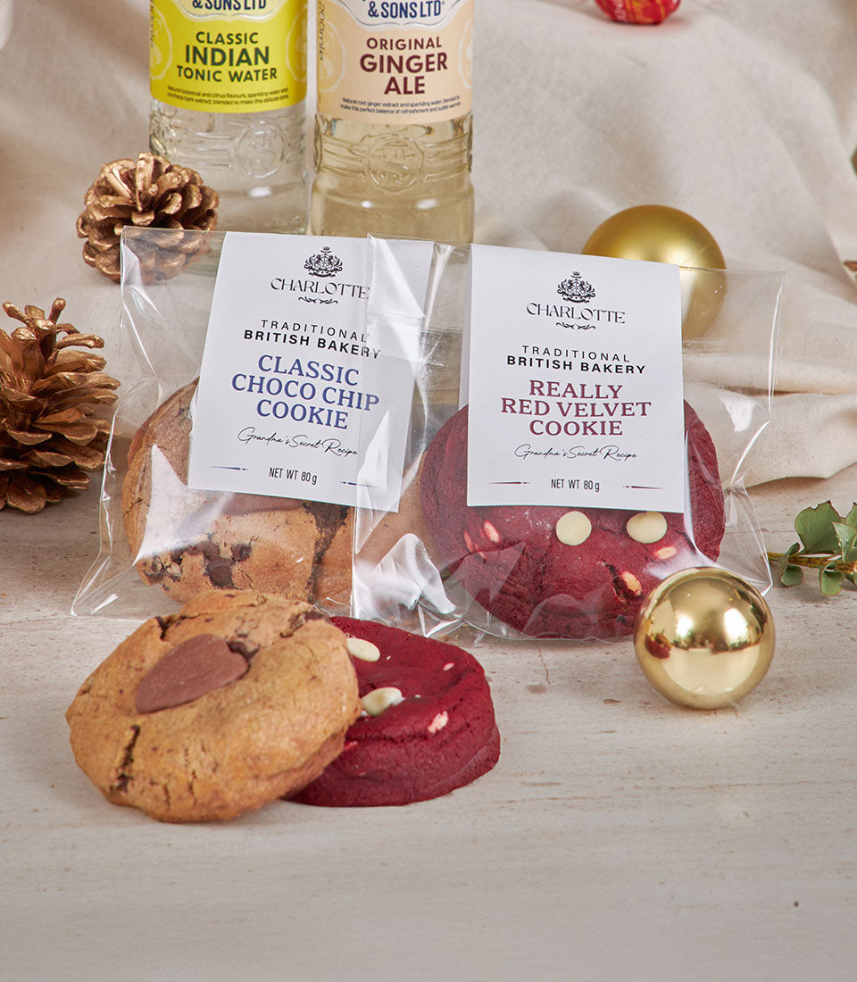 Elegant gourmet hamper with chocolate chip and red velvet cookies, tonic water, and ginger ale with gold festive accents for