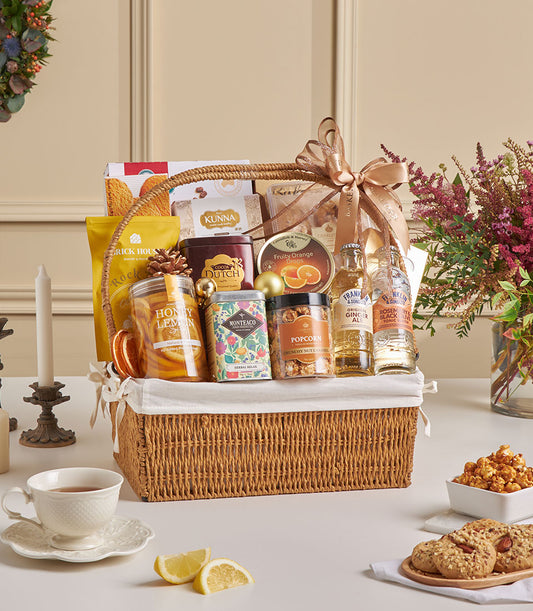 Premium gourmet gift hamper with almond cookies, cocoa, herbal tea and artisan snacks in gold-ribboned wicker basket for New