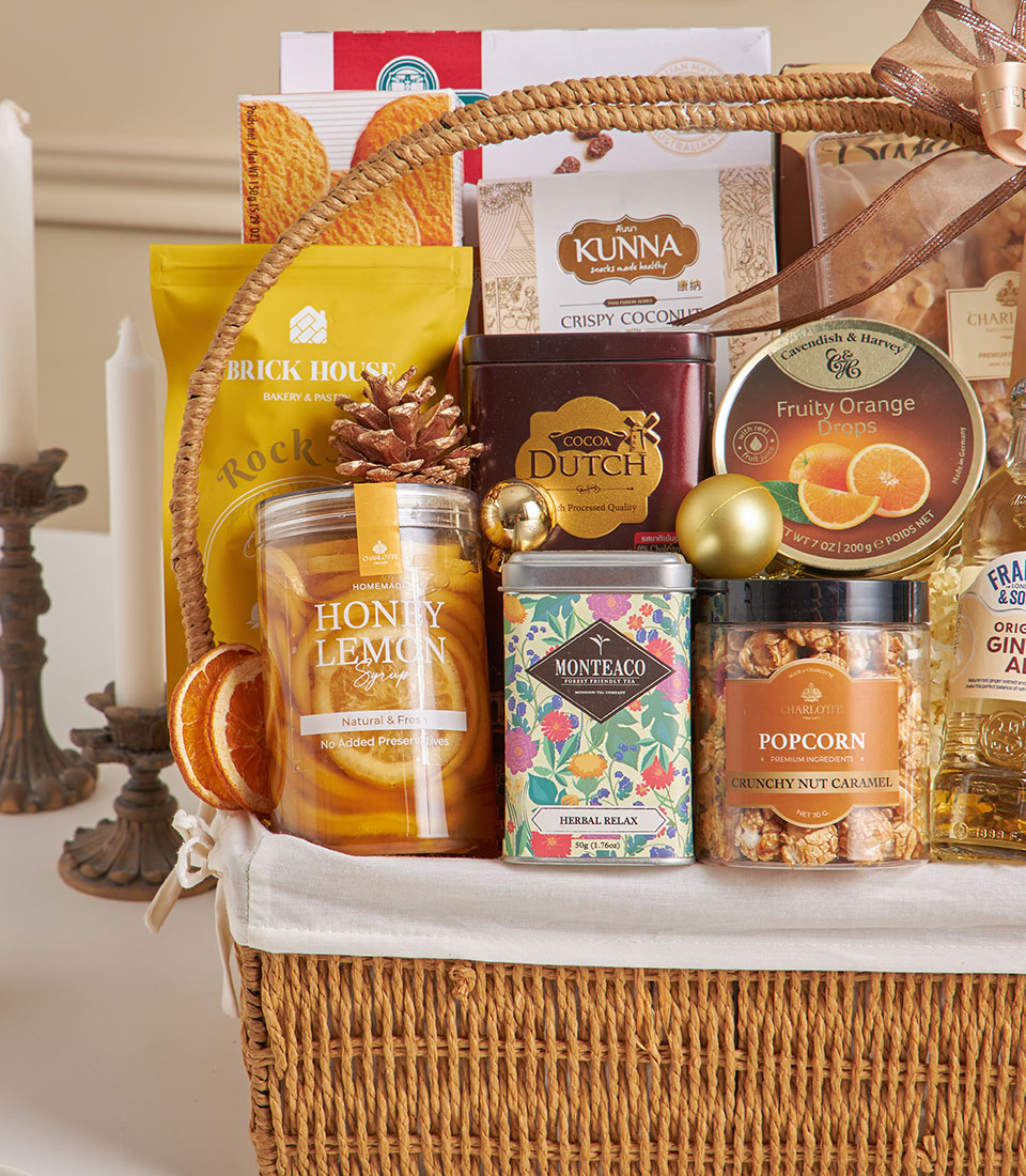 Wicker gift hamper with almond cookies, cocoa, herbal tea, honey syrup and gourmet snacks for New Year