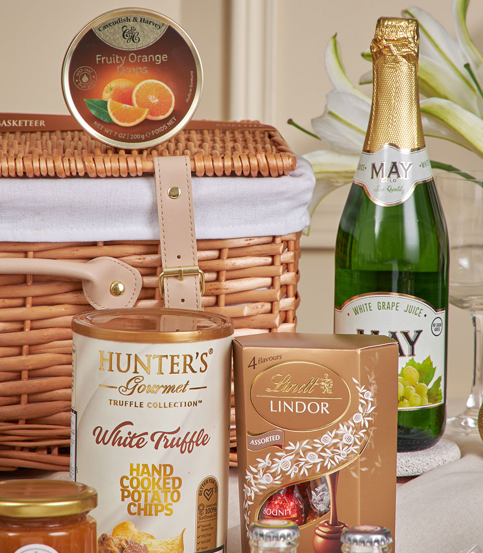 Basketeer premium hamper with orange candies, truffle chips, Lindt chocolates, and white grape juice in a charming wicker basket. Perfect corporate gift delivered in Bangkok.
