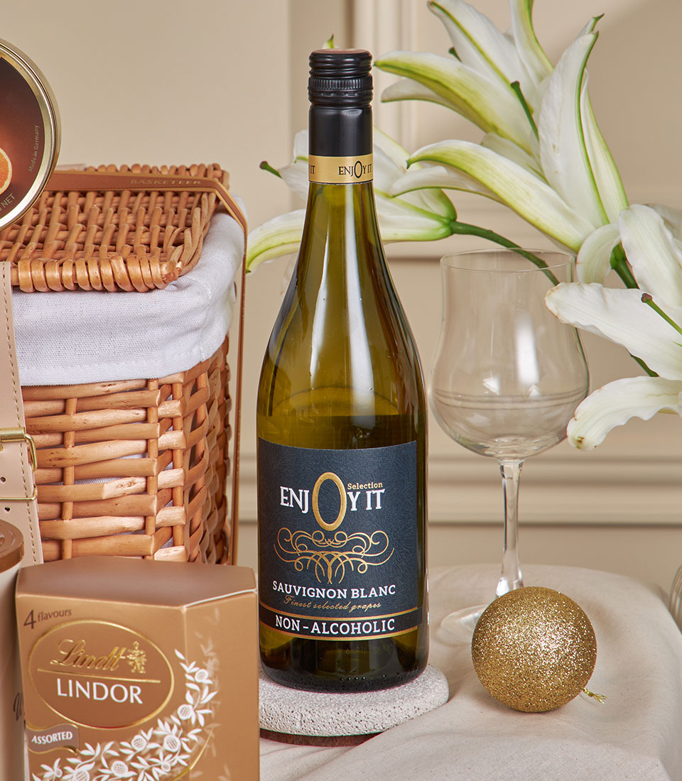 Premium golden gourmet hamper with non-alcoholic wine, artisan chocolates, wicker basket, and white lilies for New Year