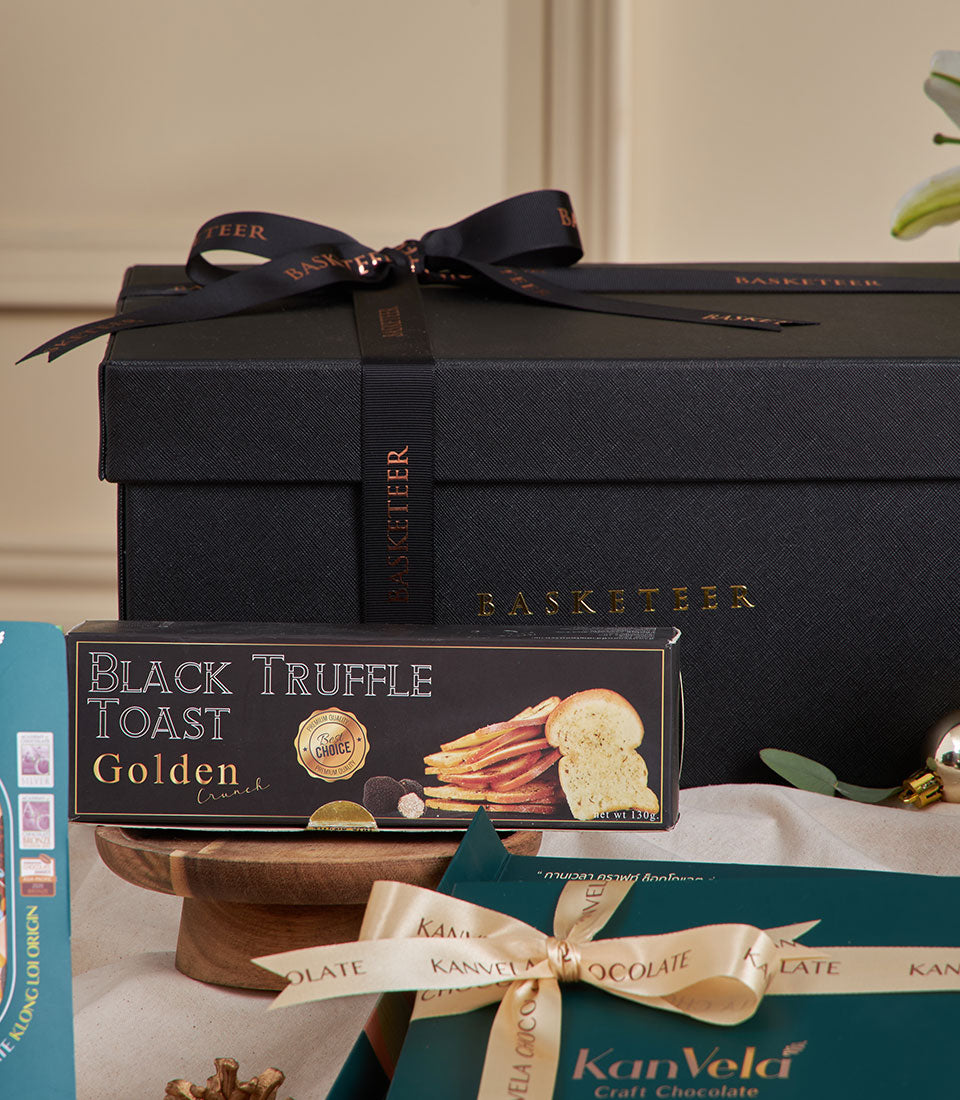 Luxury black gift hamper with gourmet chocolate, tea, and truffle toast for New Year celebrations