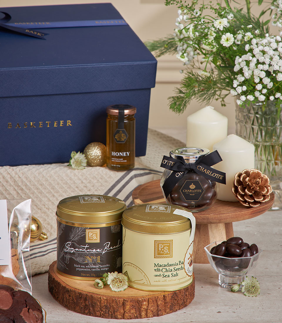 Luxury New Year gift box with gourmet treats, honey, chocolates, white flowers, and gold accents