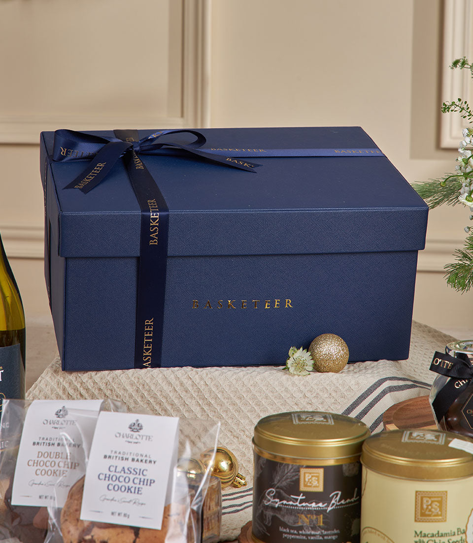 Luxury navy gift box with non-alcoholic white wine dessert, artisan cookies, gourmet teas, and gold accents for New Year