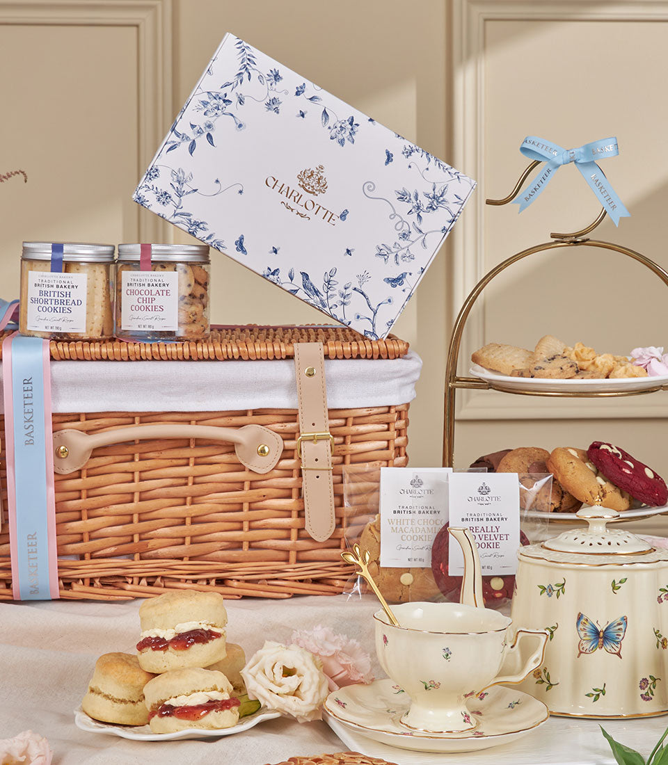 Luxury afternoon tea hamper with wicker basket, British shortbread, scones, clotted cream, fresh roses, and tiered pastry