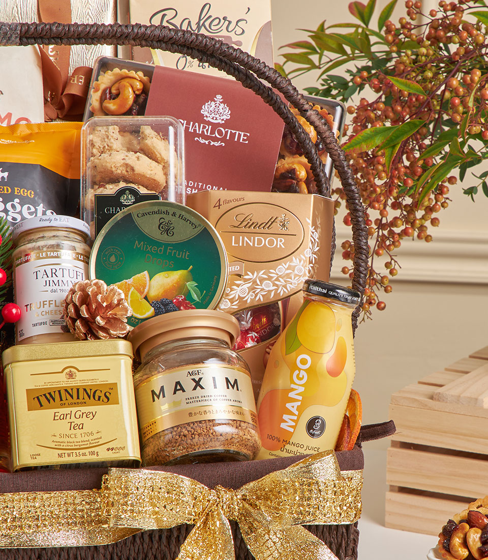 Luxury gourmet hamper with chocolates, truffle cream, and fine foods in woven basket with gold ribbon bow