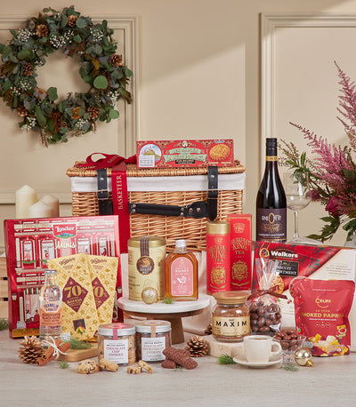 Luxury red gourmet hamper with wine, chocolates, tea, and artisan treats in wicker basket for New Year gifting