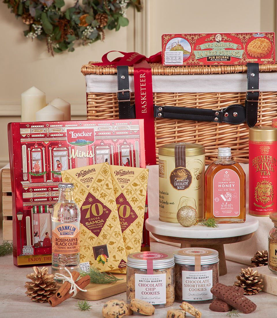Luxury red gourmet hamper with wicker basket, artisan chocolates, tea, honey, and British biscuits for New Year gifting