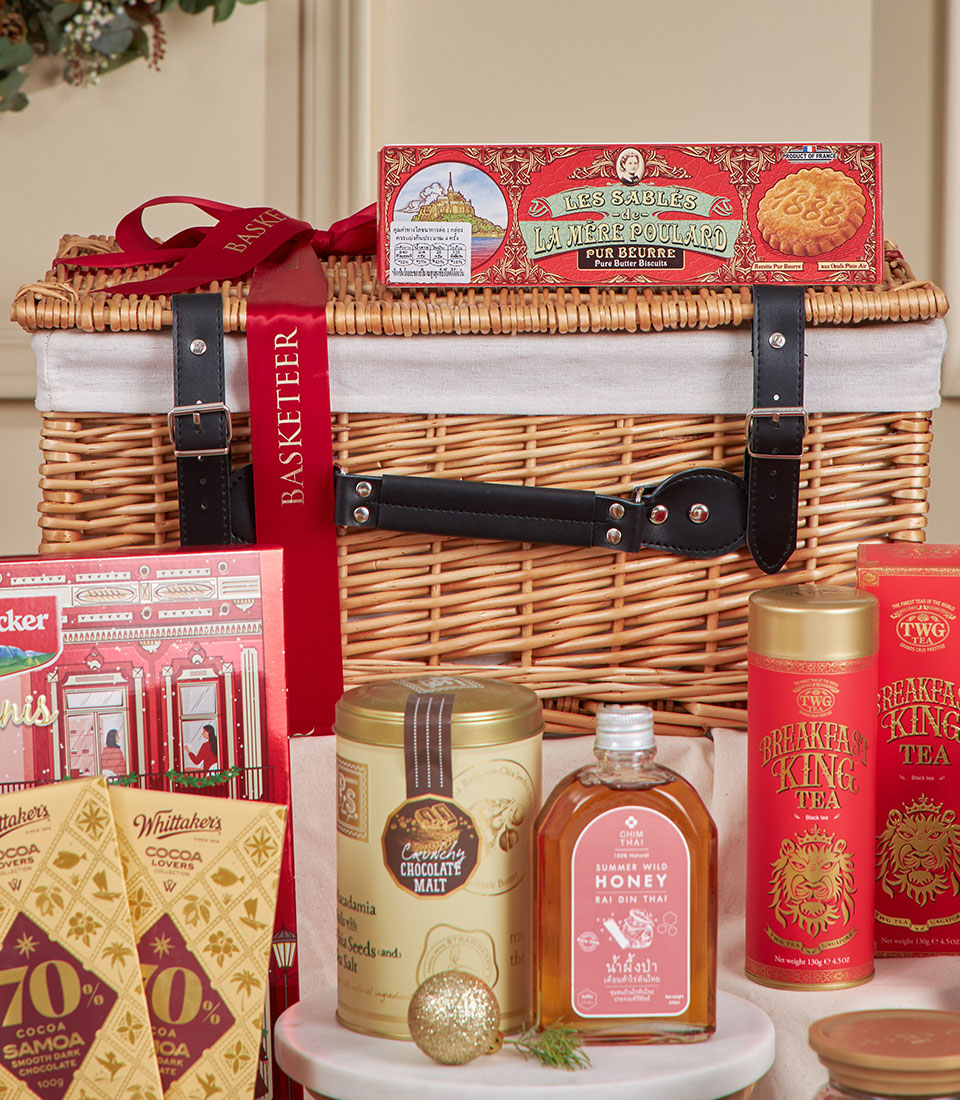 Red wicker gourmet hamper with luxury chocolates, biscuits, honey, and tea for New Year gifting