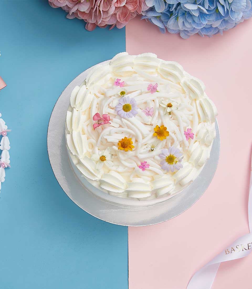 Tender Coconut Mother's Cake with whipped cream frosting, shredded coconut, and fresh flowers on silver board