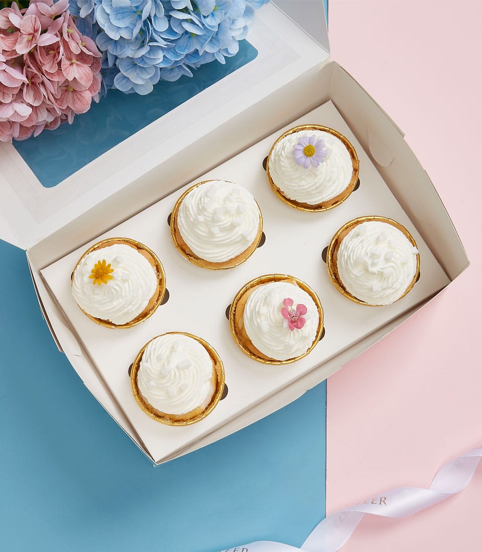 Coconut Joy cupcakes with white cream and edible flowers in gift box for Mother's Day