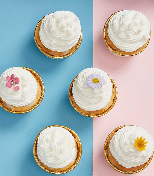 Coconut Joy cupcakes with whipped cream, coconut flakes, and edible flowers for Mother's Day