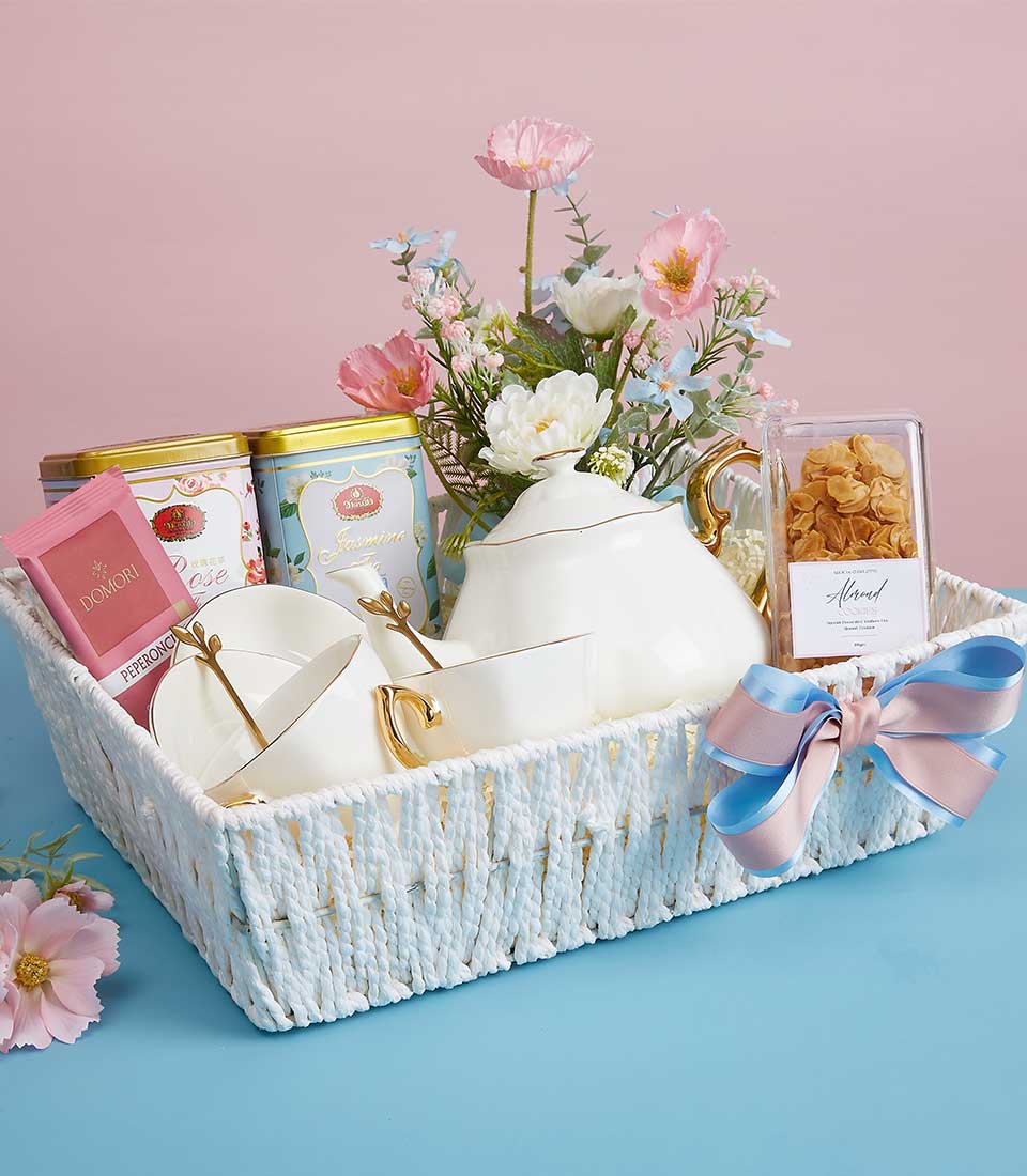 Luxury Mother's Day gift basket with white ceramic teapot, matching teacups, rose and jasmine tea tins, almond cookies, and