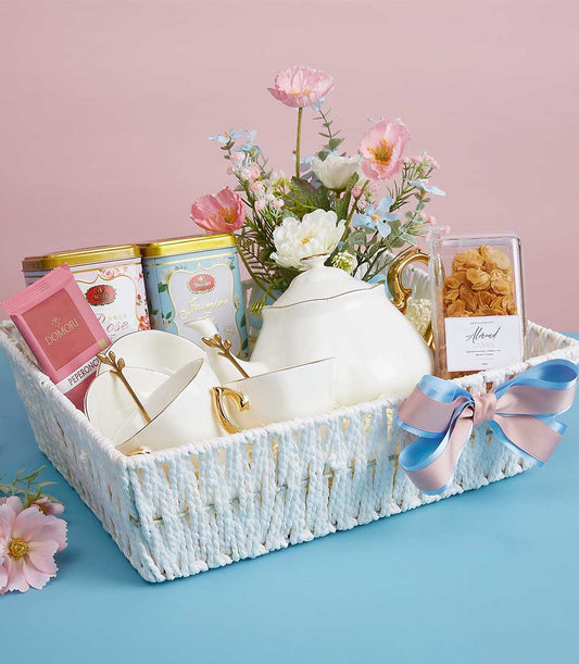 Luxury Mother's Day gift basket with white ceramic teapot, matching teacups, rose and jasmine tea tins, almond cookies, and