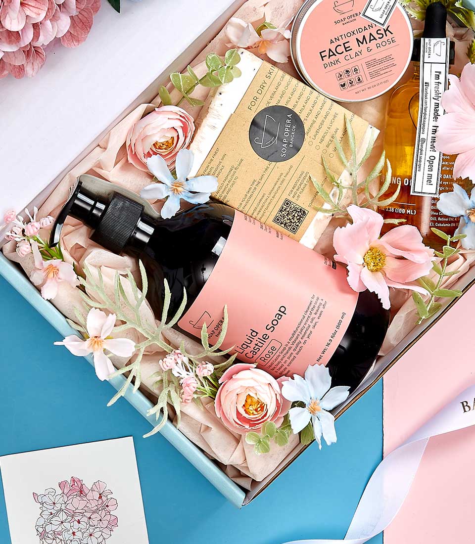 Premium spa gift set with rose castile soap, clay face mask, and skincare essentials on pink tissue