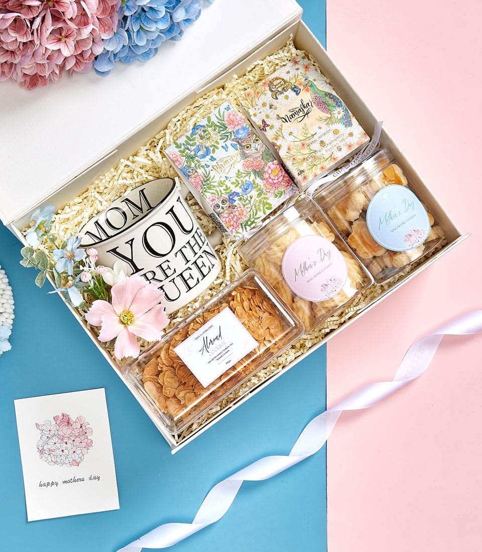 Premium Mother's Day gift box with ceramic mug, artisan cookies, and tea sachets on pink and blue background