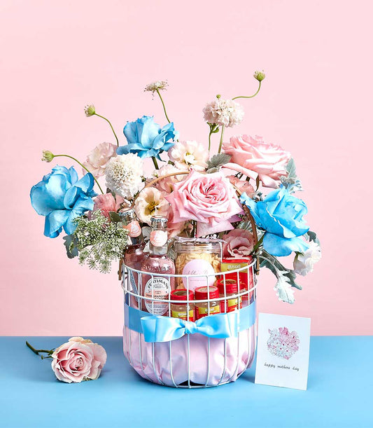 Luxury Mother's Day gift basket with bird's nest, pink grapefruit beverages, and pastel roses in white wire design