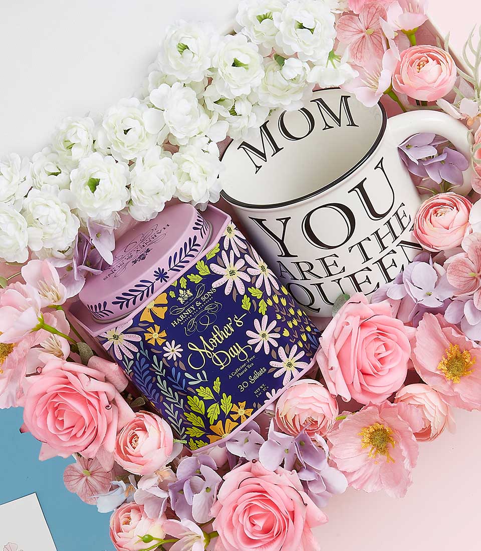 Elegant Mother's Day gift set with ceramic mug, herbal tea tin, and white and pink artificial flowers