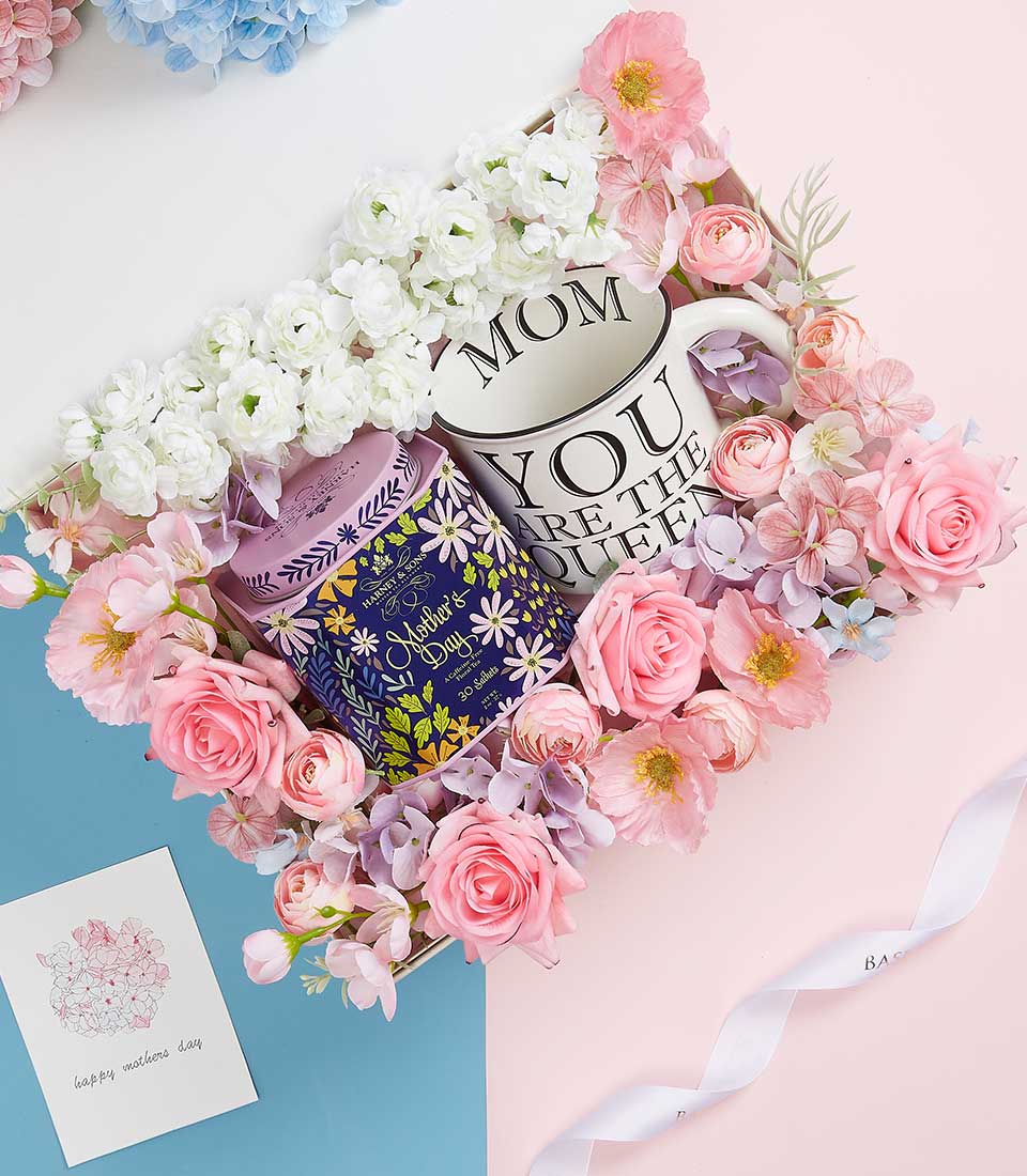 Elegant Mother's Day gift set with ceramic mum mug, gourmet tea, and artisan flowers in pink and white