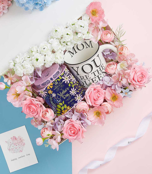 Elegant Mother's Day gift set with ceramic mum mug, gourmet tea, and artisan flowers in pink and white
