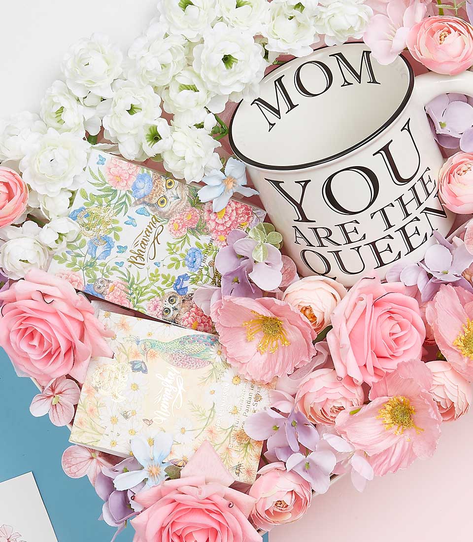 Luxury Mother's Day gift basket with ceramic queen mug, artificial florals in pink and white, and artisan keepsake boxes