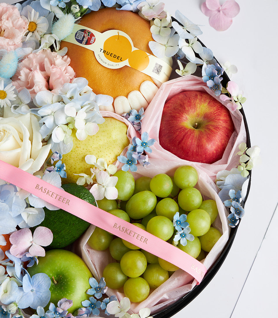 Deluxe Mother's Day fruit and flower gift box with fresh pears, apples, grapes, and premium blooms in white and pale pink