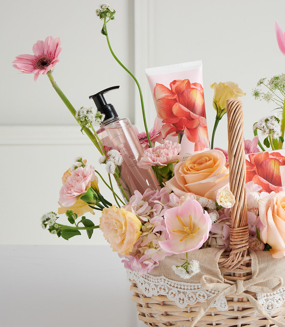 Mother's Day wicker basket with fresh pastel roses, gerberas, tulips, and spa care products with floral packaging
