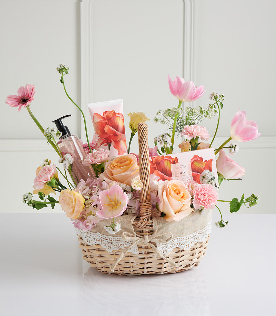 Woven wicker Mother's Day gift basket with pink roses, gerberas, tulips, spa lotion and hand cream