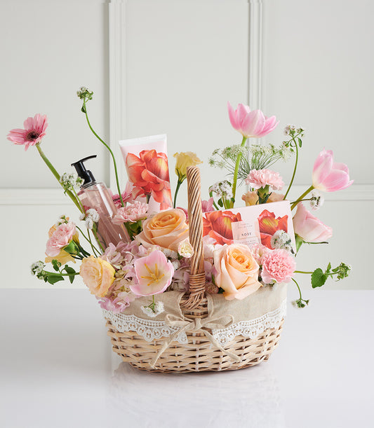 Woven wicker Mother's Day gift basket with pink roses, gerberas, tulips, spa lotion and hand cream